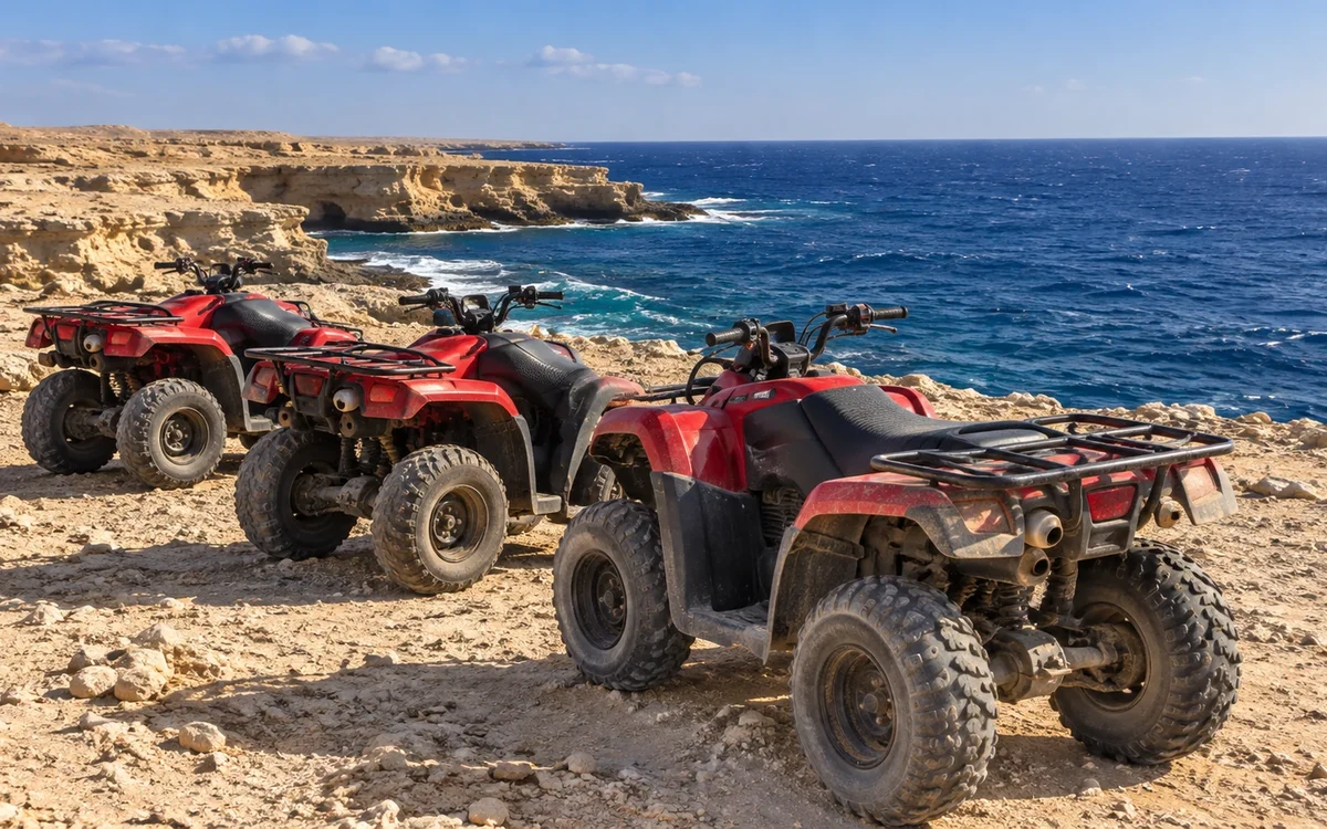 Drei geparkte Quads an einer felsigen Küste mit blauem Meer