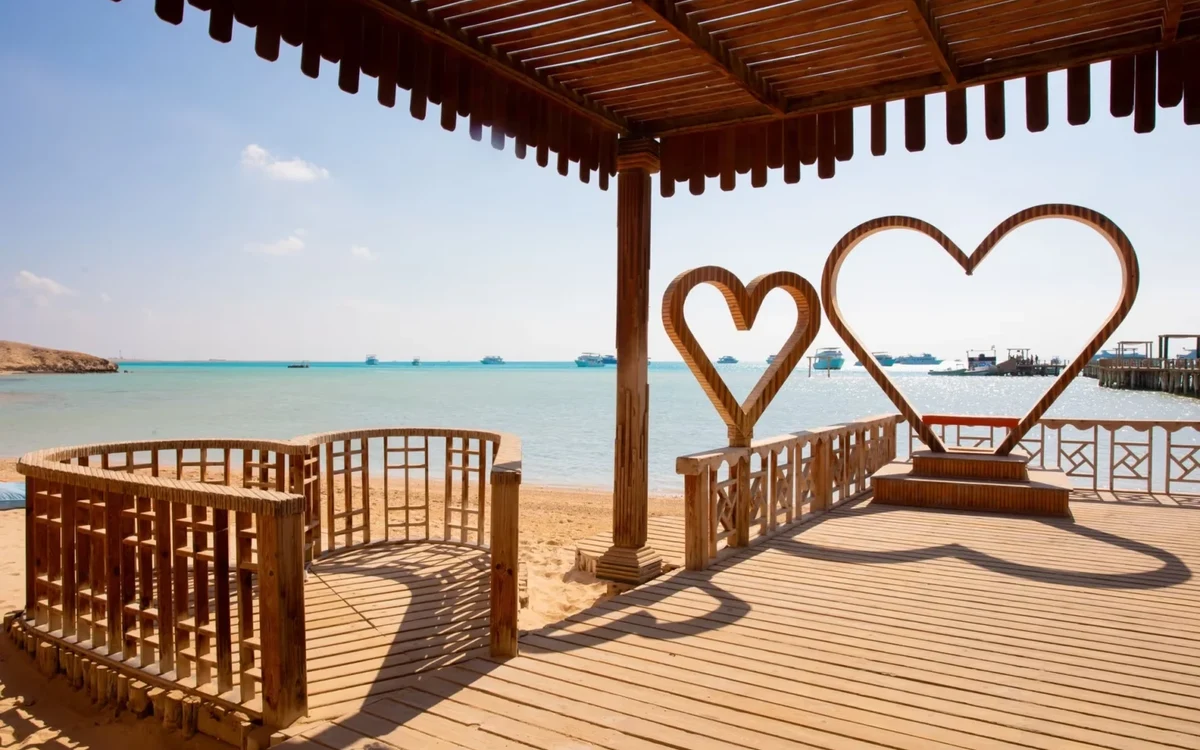 Wooden deck with heart-shaped seats beside turquoise water Wooden deck with heart-shaped seats beside turquoise water