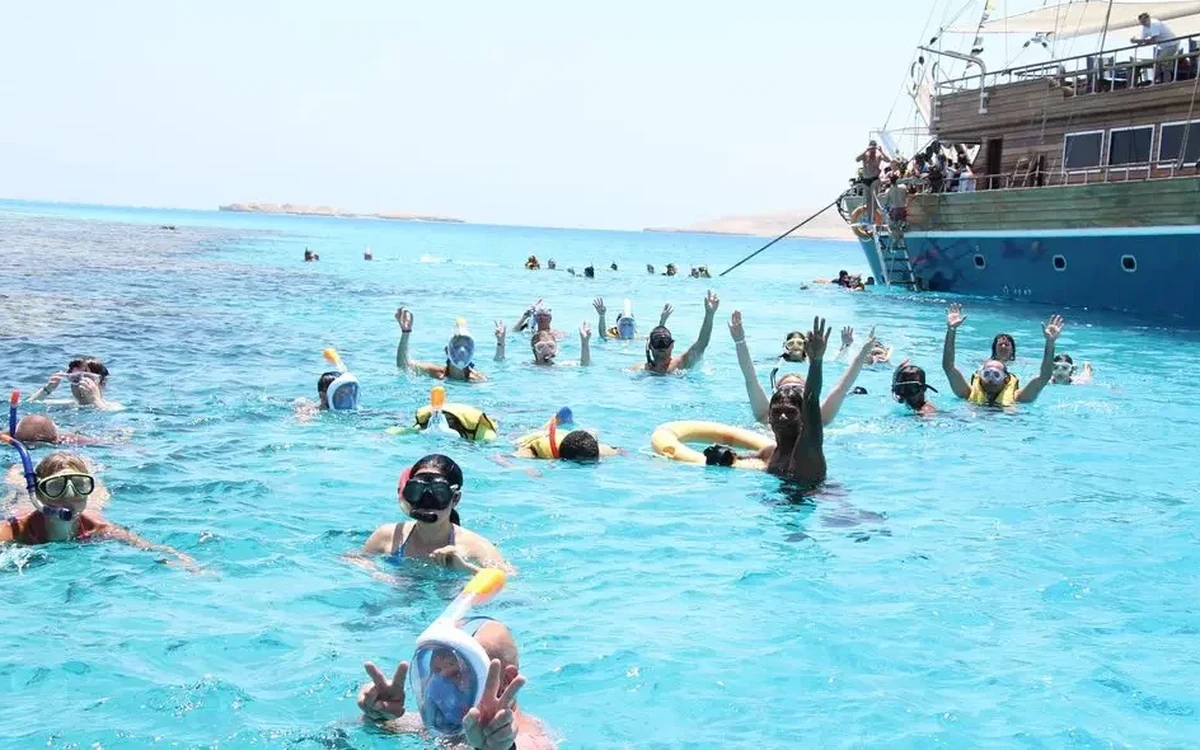 Persone fanno snorkeling accanto a una nave in legno