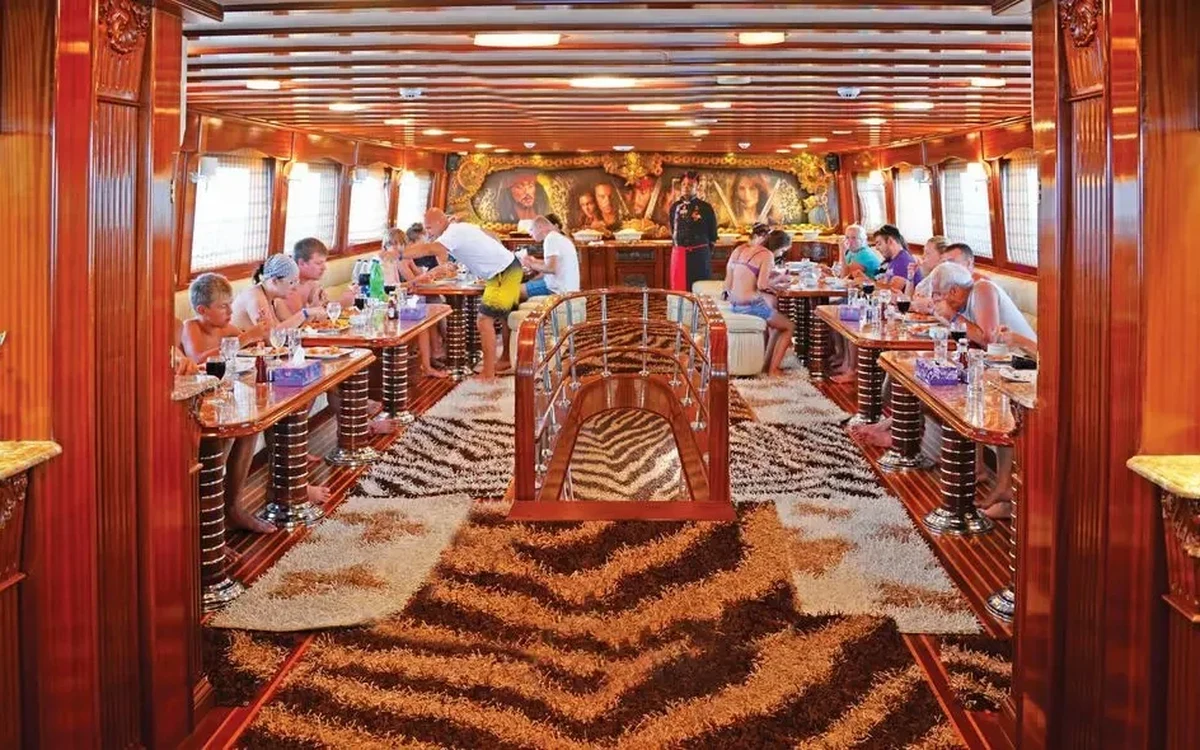 Passeggeri a pranzo dentro una nave in legno