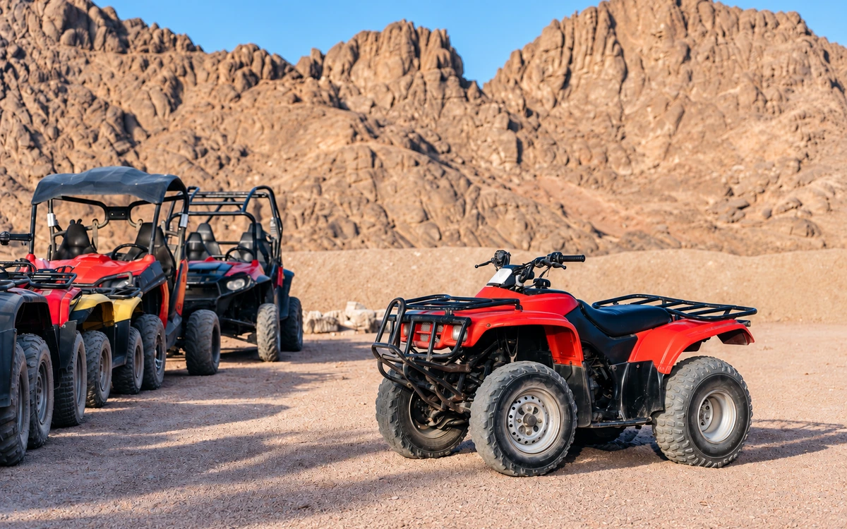 A quad bike and buggies in a rocky desert setting