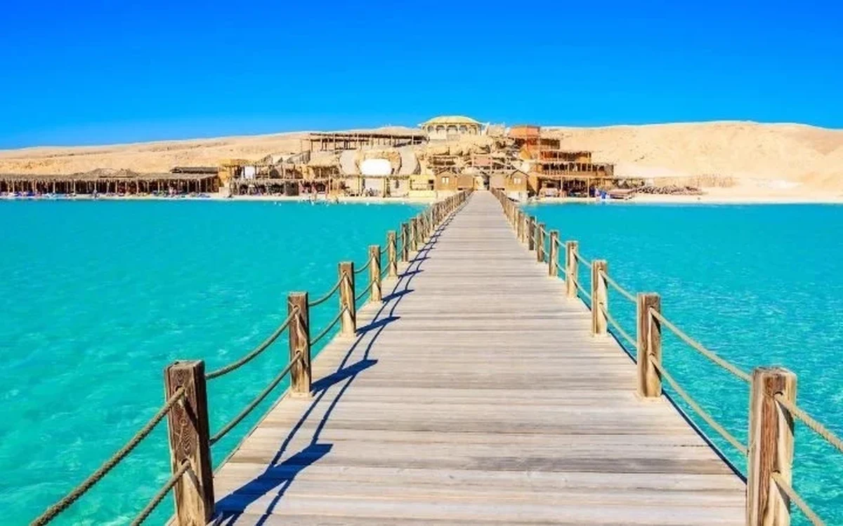 Wooden jetty crossing turquoise water toward an island beach Wooden jetty crossing turquoise water toward an island beach