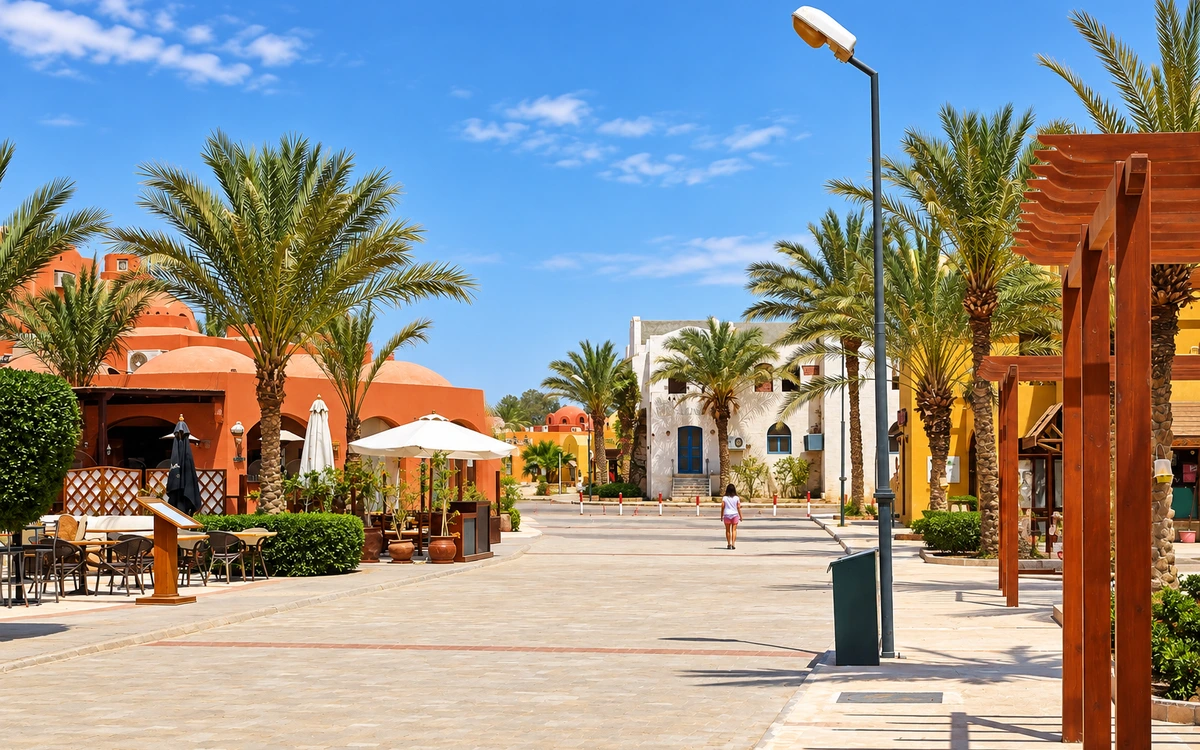 A palm-lined pedestrian street with cafes in daylight