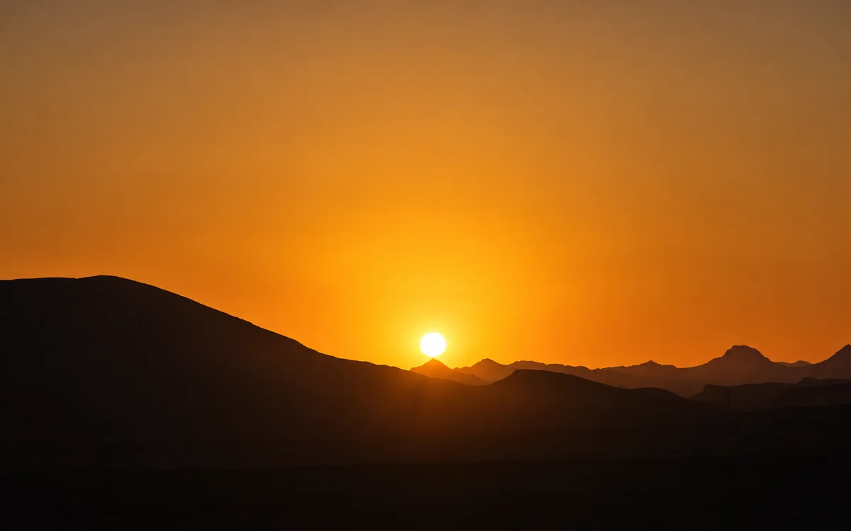 Sunset behind desert mountain silhouettes in the Eastern Desert