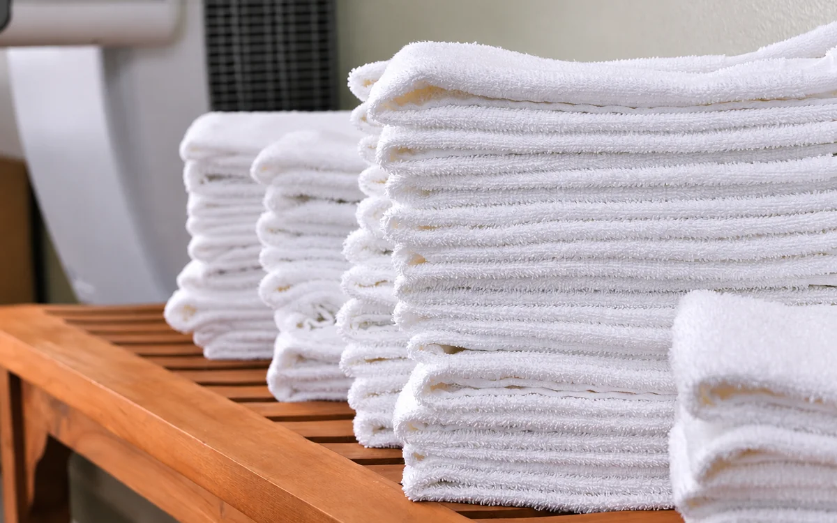 Representative image: stack of white spa towels on a wooden bench